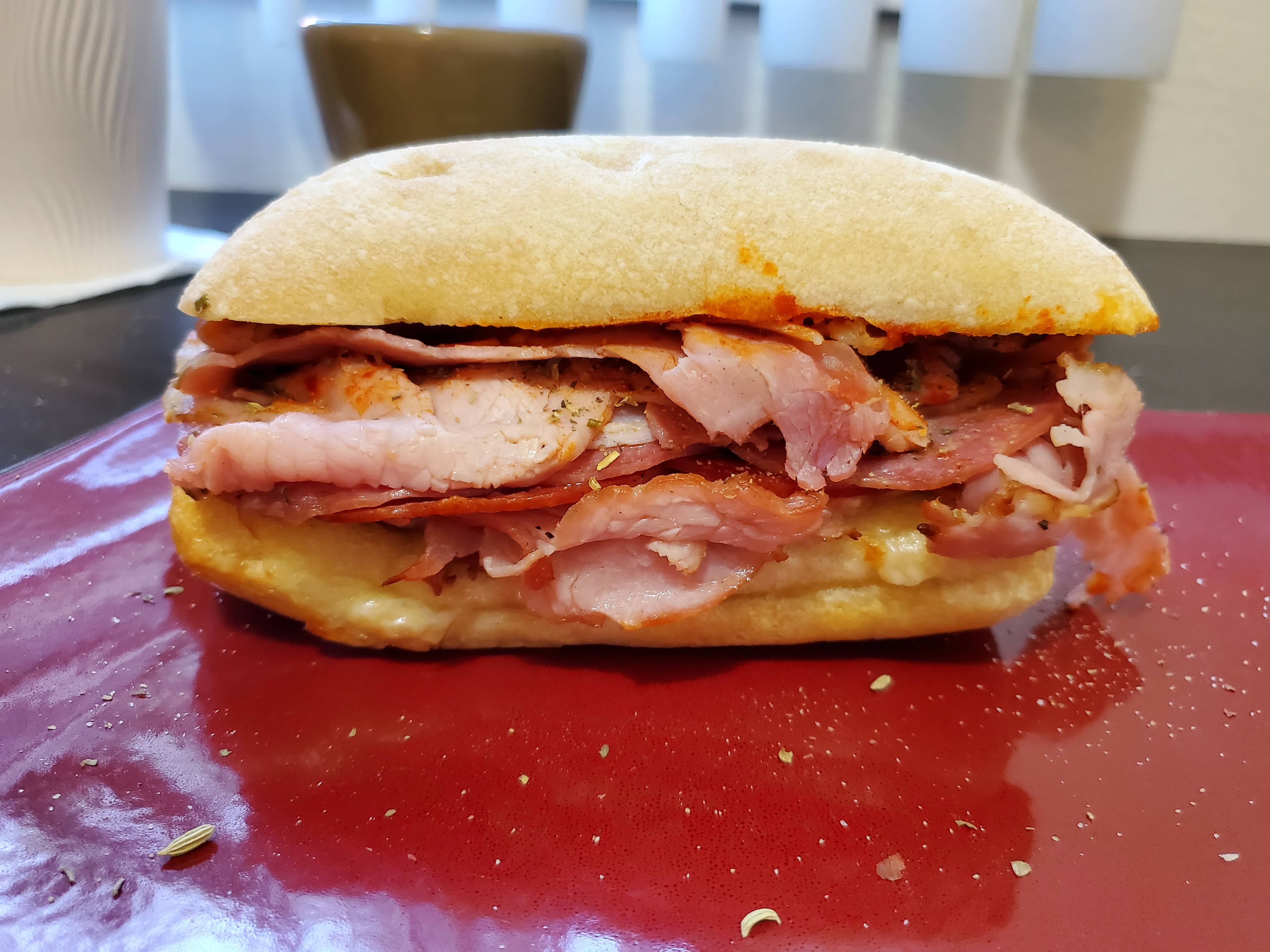 A sandwich with rosemary ham, pepperoni, salami, provolone, and a spicy pepper spread
